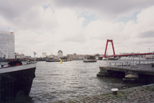1994-142 De Nieuwe Maas met rechts de steunpilaren van de gesloopte spoorbrug, de Willemsbrug en op de achtergrond ...