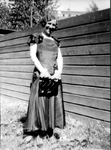 2002-1925 Portret van een jonge vrouw in trouwjapon in een tuin.