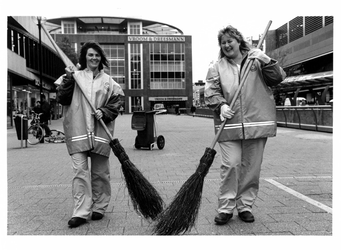 2003-788 2 vrouwen aan het werk op het Beursplein voor het project Rotterdam Schoon van de ROTEB. Zij dragen jassen met ...