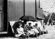 XXXIV-28-13 Een groep kinderen onder een paraplu achter de poffertjeskraam bij de Veemarkt en Veemarktstraat, tijdens ...