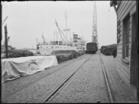 1976-5698 Schiehaven, op de kade liggen goederen onder zeilen van de firma Binghem bij Wambersie