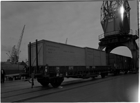 1976-7839 Overslag in de haven. Het laden / lossen van houten kisten in een treinwagon aan de kade.