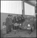 10561 Instructie voor garagepersoneel bij meetapparatuur en afstellen van autoverlichting rond een Volkswagen Kever.