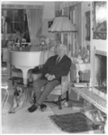 10815-3 Eduard Flipse zit in zijn huiskamer aan de Rozenburglaan naast de piano en zijn hond.