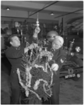 11304 In een brandweerkazerne zijn twee geuniformeerde brandweerlieden bezig een kerstboom op te tuigen; de ...