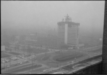 21261-6-7 Hoogbouw Bouwcentrum in aanbouw op de hoek Weena en het Kruisplein tijdens mist.