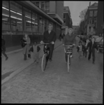 23928-1-11 Zuster M.P.C. Haaijer en burgemeester W. Thomassen fietsen in de Eendrachtsstraat.