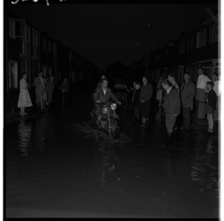 3269-1 In sommige straten van Hoogvliet staan bewoners na de wolkbreuk tot en met hun enkels in het water.