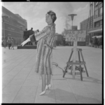 3468-2 Mannequin van Nico Nachtegall in lange bontjas op Stadhuisplein bij bord 'Pas op, oliespatten'.