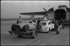 4626 Autocoureur Godin de Beaufort met sportwagen bij vrachtvliegtuig op vliegveld Zestienhoven.