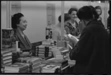 5023-1 Dames bij een kraam met kookboeken. Rechts van paaltje: Henriette Holthausen