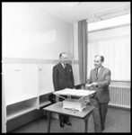 7623-1 Directeur GGD-Rotterdam, dr. L. Burema (links) en wethouder G.Z. de Vos staan bij een babyweegschaal in het ...