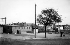 1976-2422 Gezicht vanaf het Stationsplein op een gebouw-en spoorlijn. En een straaturinoir.
