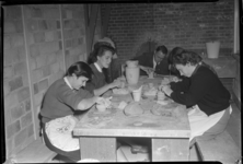 2006-15792 Een cursus pottenbakken in Ons Huis aan de Gouvernestraat. Een groepje mensen aan een tafel is druk bezig ...