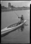 2006-15869 Een man in een kano op een brede vaart te Schiedam. Op de achtergrond een spoorlijn en een molenstomp.