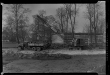 THO-116 Een kraanmachinist graaft grond af in het Park bij de opbouw van de manifestatie E '55. Aan de kraan hangt een ...