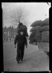 THO-133 Kolenboer H. v. d. Weijen loopt met een zak met kolen op zijn rug op de Havenstraat ter hoogte van de Lage ...