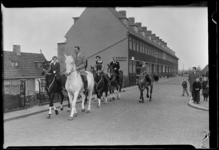 THO-156 Ruiters rijden met paard over de Zestienhovensekade. Omstanders lopen mee. Op de achtergrond is een schoenmakerij.