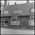 THO-1587 Op een raam van een woning in Vreewijk staat 'Verkocht'. Links een winkel met levensmiddelen.