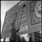 THO-1646 Frits Mullens plakt aanplakbiljetten van Circus Mullens op een bord. Het circus staat op de Kruiskade van 3 ...