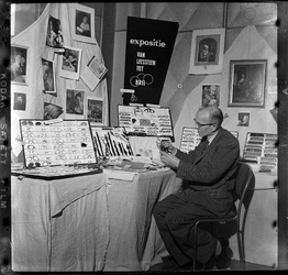 THO-1969 Tijdens een beurs voor verzamelaars in gebouw 'De Twaalf Provinciën' zit een man bij een stand met leesbrillen.