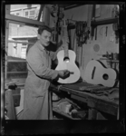 THO-2060 De Schiedamse gitaarbouwer C. Swagemakers staat met een gitaar in zijn werkplaats.