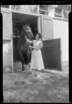 THO-696 Vrouw staat met een paard bij een stal van de Rotterdamse Manege voor de CHIO aan de Kralingseweg bij het ...