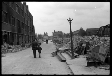 1980-5055 Een man en een klein jongetje wandelen door de door het bombardement van 14 mei 1940 getroffen Dijkstraat in ...