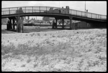 1980-5276 De Karnemelksbrug over de gedeeltelijk gedempte Rotte. Op de achtergrond rechts het schoolgebouw van de r.k. ...