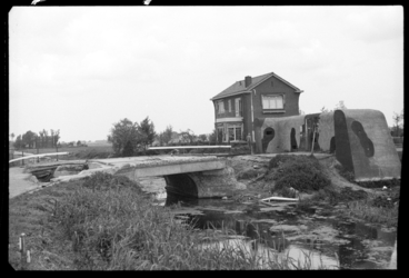 1980-5622 Een antitankmuur en een onklaar gemaakte brug over een sloot bij de Terbregseweg.