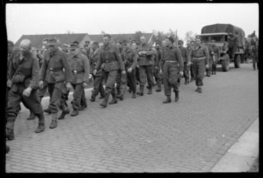 1980-5629 Duitse krijgsgevangen lopen onder geallieerde bewaking over de Hoofdweg bij Terbregge. Achteraan rijdt ...