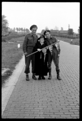 1980-5634 Twee geallieerde militairen poseren op de Hoofdweg in Terbregge met een oudere vrouw die een stok met drie ...