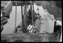 1980-5818 Heiwerkzaamheden vanaf het water in de Zalmhaven. Naast het schip met de heimachine drijven houten heipalen ...