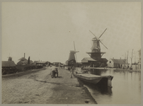 XXXI-204 De Rotterdamse Schie met de molens 'Het Haantje' en 'Vlaggeman'. In het water ligt een boot, en op de weg ...
