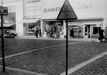 1977-646 Oversteekplaats voor de voetgangers met waarschuwingsbord en witte lijnen. Op de achtergrond de noodwinkels ...