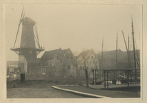 XIV-282 Een rij pakhuizen aan de Achterhaven. Links de molen De Distilleerketel op het Middenhoofd. op de voorgrond het ...