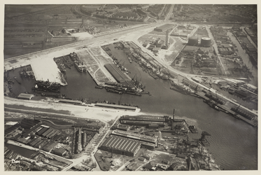 VII-372-00-01-2 Luchtfoto van de Merwehaven, vol met schepen, in Nieuw-Mathenesse, met rechts de Benzinehaven en ...