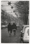 1989-4746 Twee fietsers in de Zwart Janstraat, Noorderboulevard. De straat is versierd met kerstverlichting. Uit een ...