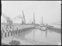 L-1834 Heiwerkzaamheden door bouwvakkers van de Hollandsche Beton Maatschappij NV in een haven. Rechts ligt een ...