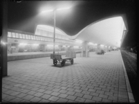 L-2311 Avondopname van verlichte overkappingen op de perrons van het nieuwe Centraal Station. Op het perron staan ...