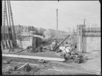 L-3149 Betonwagens rijden in een bouwput bij de bouw van de Leuvesluis. Op de achtergrond wordt beton gestort. Links ...