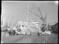 L-455 Twee mannen laden een binnenvaartschip vanaf de kade van de Merwehaven met jutezakken. Op de voor- en achtergrond ...