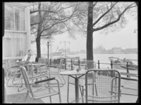 L-700 Een man zit op het terras van café Bellevue aan de Parkkade langs de Nieuwe Maas. Op de achtergrond varen ...