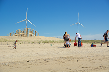 MR-133 Strandbezoekers op de Tweede Maasvlakte met op de achtergrond windmolens en het kunstwerk De Zandwacht.