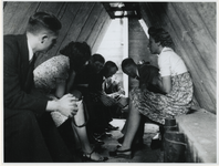 1968-271 Een groepje mensen zoekt tijdens een luchtalarm bescherming in een schuilkelder.