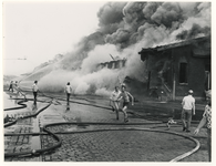 1976-1844 Een deel van de brandende loods stort in.