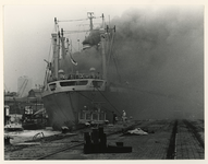 1977-1621 De brandende Karonga geladen met boomstammen aan pier 6 in de Waalhaven.