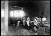 201 Bakkers kneden broden aan een grote werktafel bij bakkerij Jansse aan de Oranjeboomstraat.