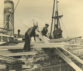 FD-3223 Mannen bezig met de overslag van houten planken in de haven.