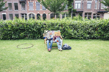 2014-43 Twee volwassenen en een kind zitten buiten op een klapstoel en lezen de krant en een kinderboek. De foto is ...